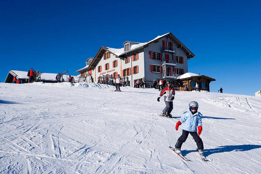 Skiers on slope, alpine lodge Maennlichen in background, Maennlichen, Grindelwald, Bernese Oberland, Canton of Bern, Switzerland