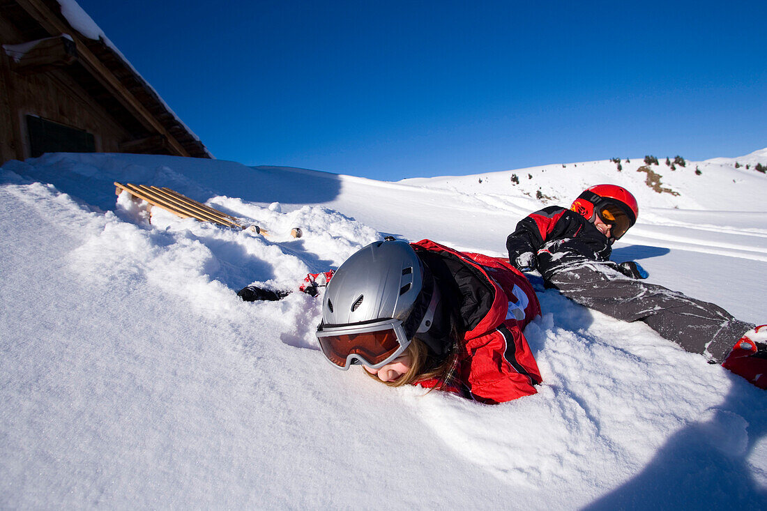 Children lying in snow, Maennlichen, Grindelwald, Bernese Oberland, Canton of Bern, Switzerland
