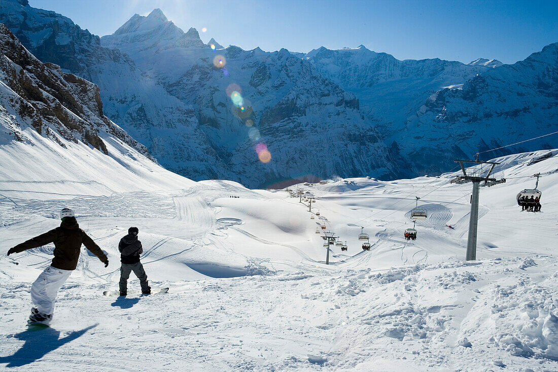 Snowboarders on slope near ski lift, First, Grindelwald, Bernese Oberland, Canton of Bern, Switzerland