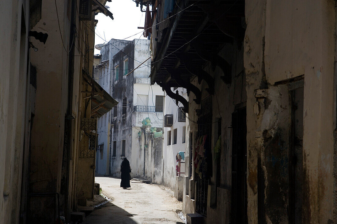 Muslim woman walking through lane in Old Town, Mombasa, Kenya