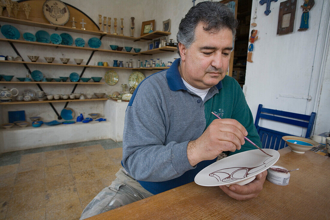 Efthymioos Symeou, ceramic artist and craftsman painting a plate, Pottery workshop, Larnaka, South Cyprus, Cyprus