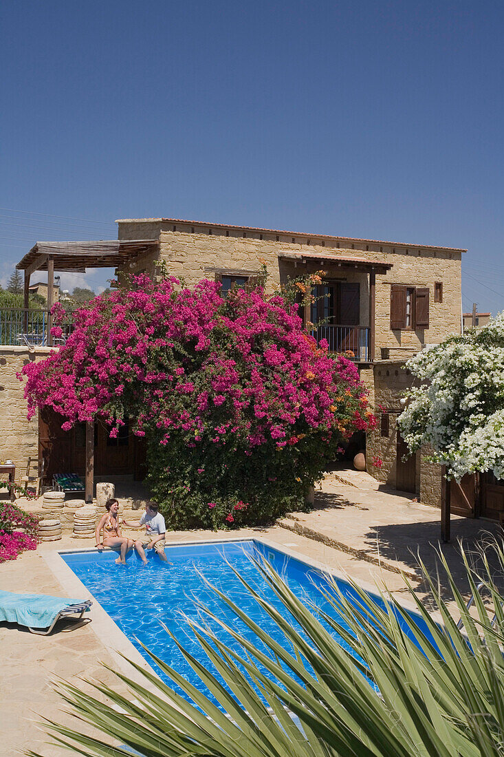 A couple sitting on the edge of the pool, Traditional guesthouse and pool, Cyprus Villages Traditional Houses Ltd., Agrotourism, Tochni, near Larnaka, Cyprus