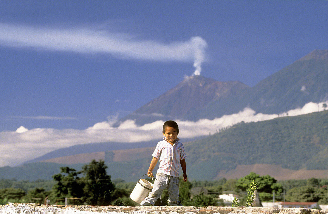 Mayan boy and the Volcán de Fuego in background. Antigua Guatemala. Guatemala