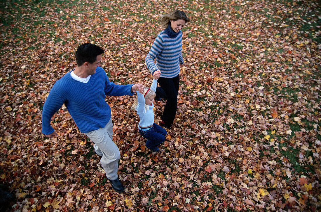 Family running through fallen leaves