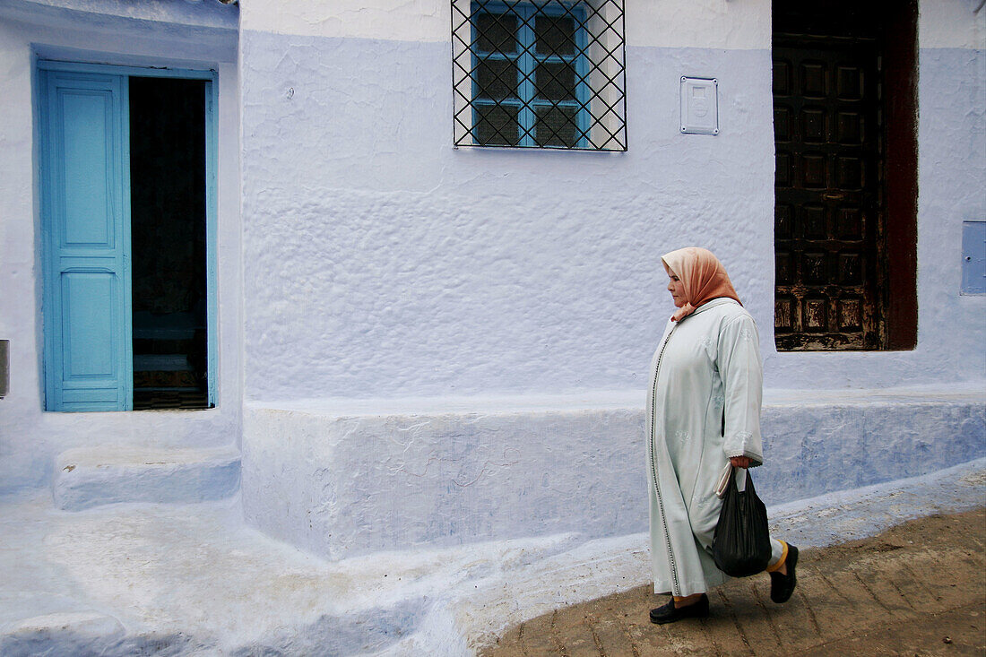 Woman walking in typical street in Chefchaouen, Morocco.