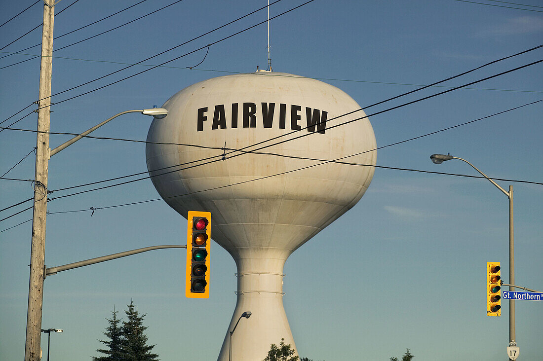 A water tower, amid traffic lights and wires, showing the name of the town. Canada.