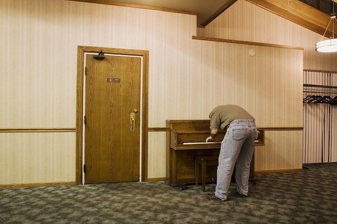 A man playing the piano in a party room in a hotel.