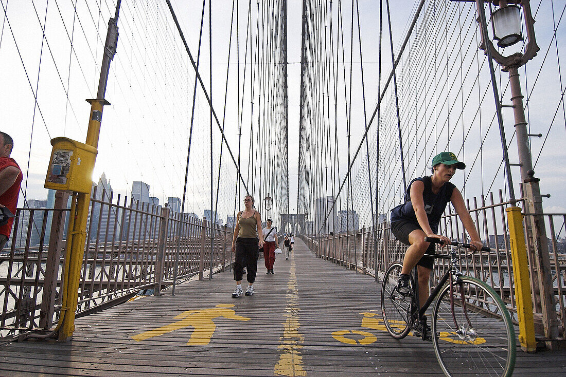 Pedestrians and biker on the Brooklyn Bridge. New York City. New York. United States
