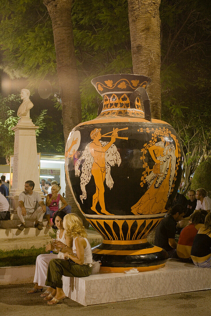 People at a Wine Festival sitting in front of a huge sculptur of a pitcher, Limassol, Cyprus