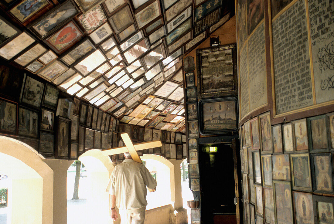 Man carrying a cross through Chapel of the Miraculous Image, Altotting, Bavaria, Germany