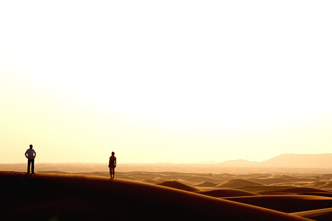 Silhouette of Couple in the Desert watching sun set, Dubai, United Arab Emirates, UAE