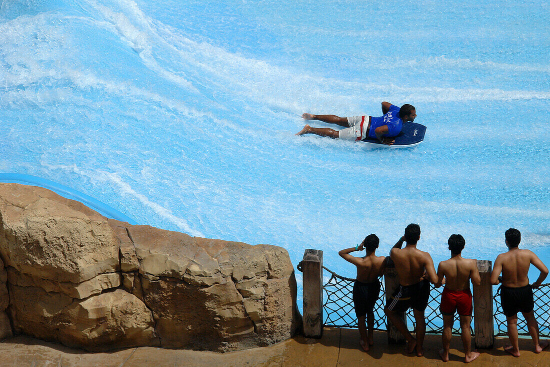 Four men watching a person on a surf board at Wild Wadi Waterpark, Dubai, United Arab Emirates, UAE