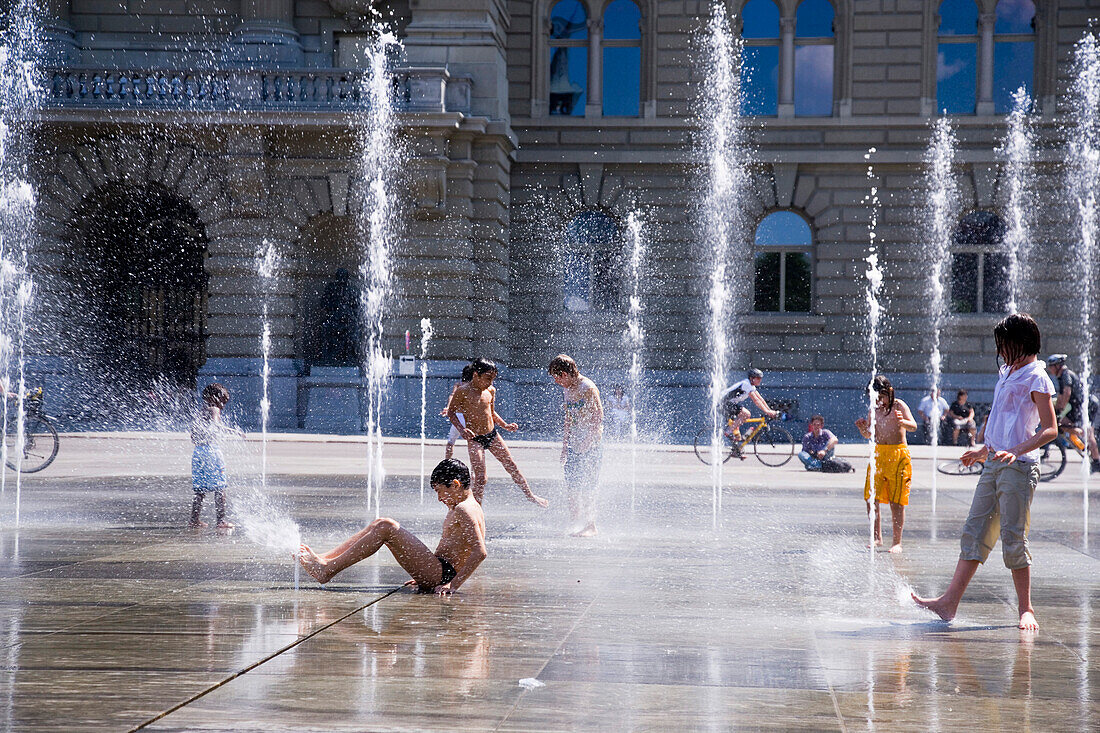 Children playing in the trick fountains and water gardens in front of the House of Parliament on Parliament Square, Bundeshaus, Bundesplatz, Old City of Berne, Berne, Switzerland
