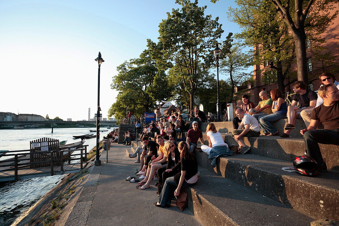 People relaxing on the steps of the promenade, River Rhine, Riviera Klein-Basel, Basel, Switzerland