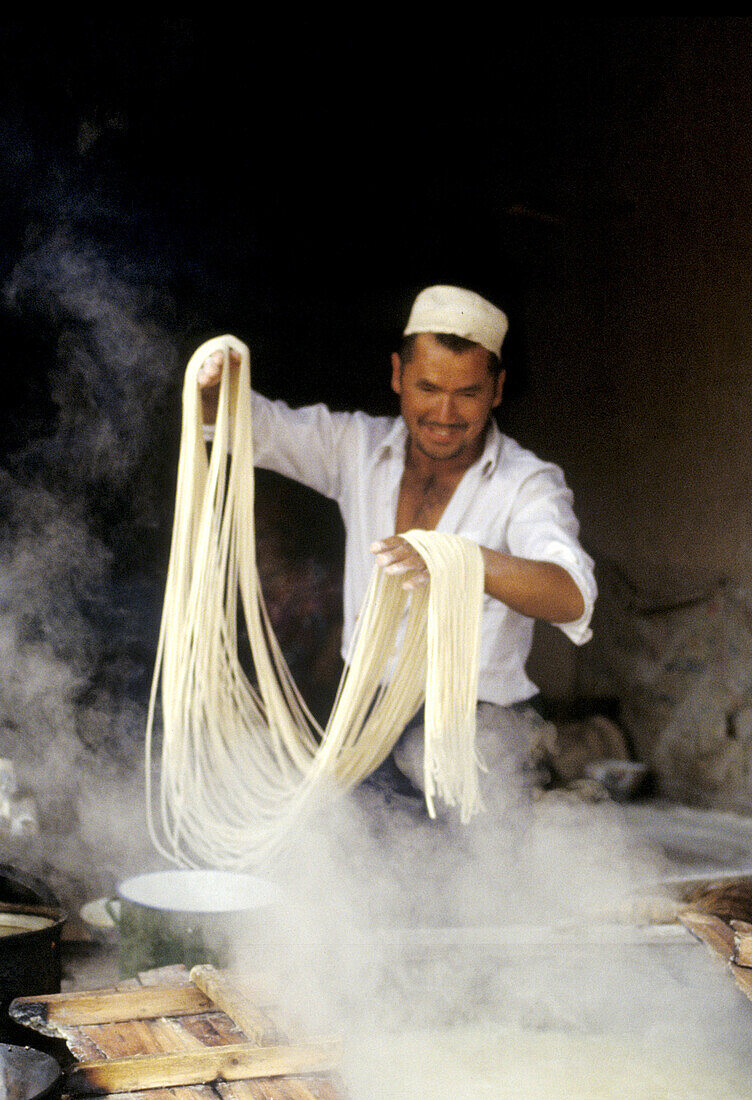 Making noodles in a small food stall on the Camel Market of Kashgar, Xingjang Province. China