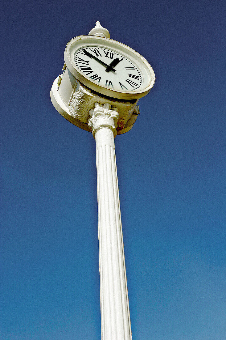 Public clock seen from below against a deep blue sky.