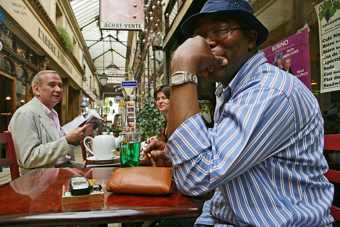 Afrikanischer Gast lacht in die Kamera, Geschäftsmann beim Kaffee trinken, Passage des Panoramas, 1799 gebaut, Boulevard Montmartre, 2 Arrondissement, paris, Frankreich
