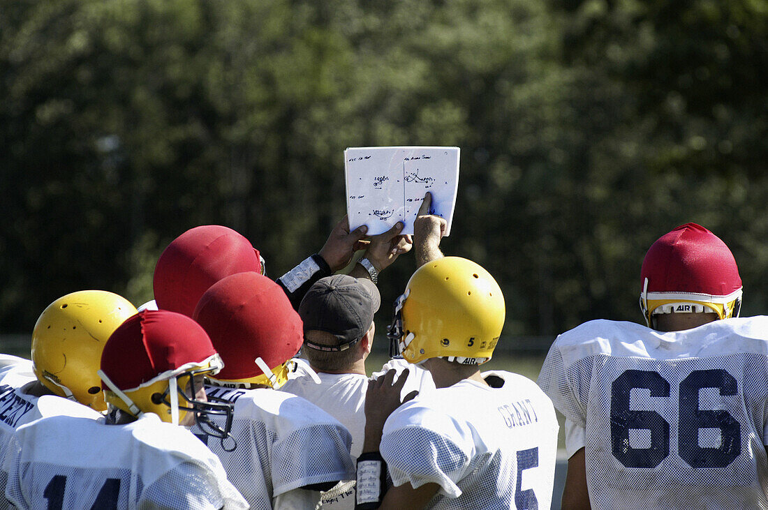 Football coach holds up play book for all players to see