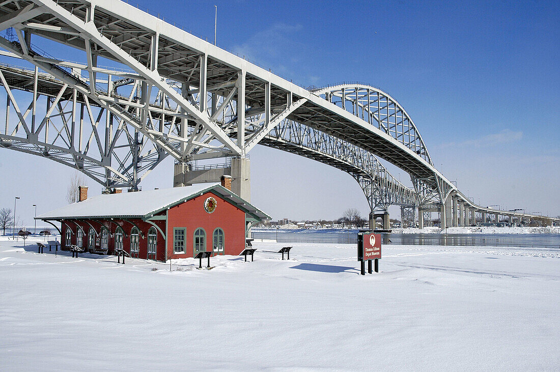 View of the Blue Water International Bridge at Port Huron Michigan during a winter snow storm with Thomas Edison Train depot in foreground