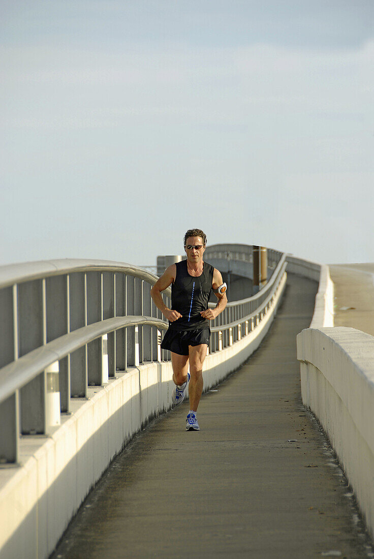 Adult male runs across a bridge in Jacksonville Florida for exercise and health. USA.