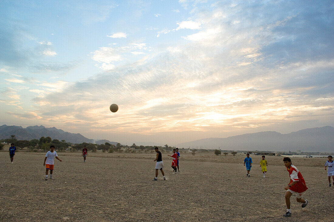 Boys playing football at sunset, Dibba, Oman