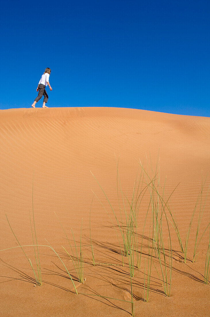 Woman walking on dune, Arabian Desert, United Arab Emirates