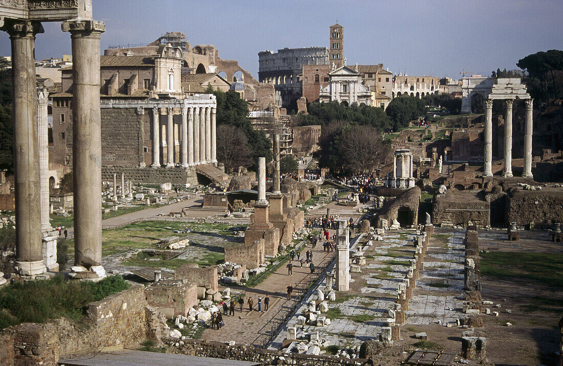 Saturn Temple (left), Via Sacra (centre), Temple of Castor and Pollux (right) and Colosseum (in background). Roman Forum, Rome, Italy