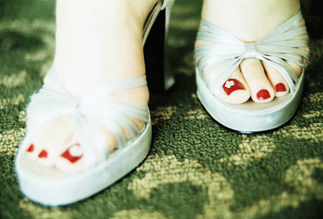Damenfüße mit lackierten Nägeln in Sandalen