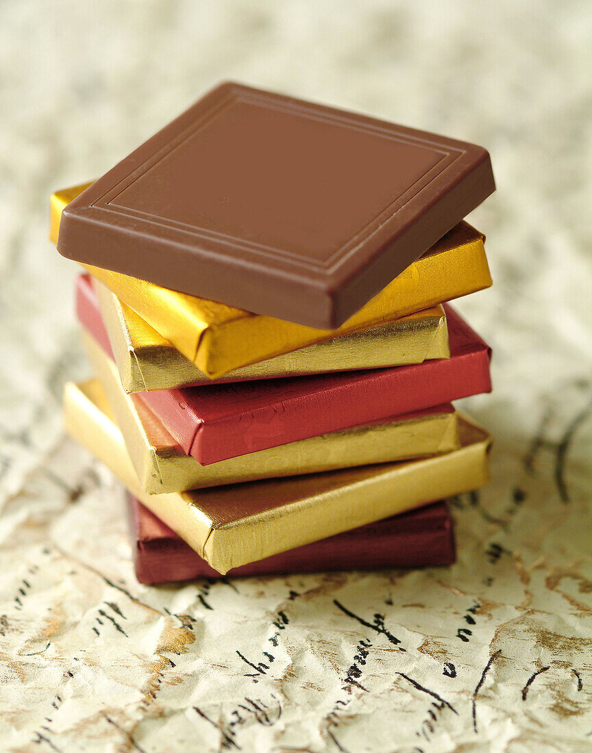 Thin chocolates stacked on florentine paper