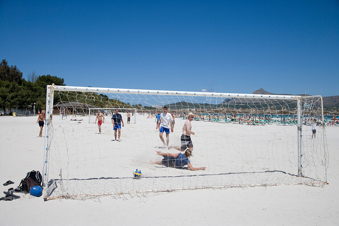 Junge Menschen spielen Fussball am Strand, Port d'Alcudia, Mallorca, Balearen, Spanien, Europa