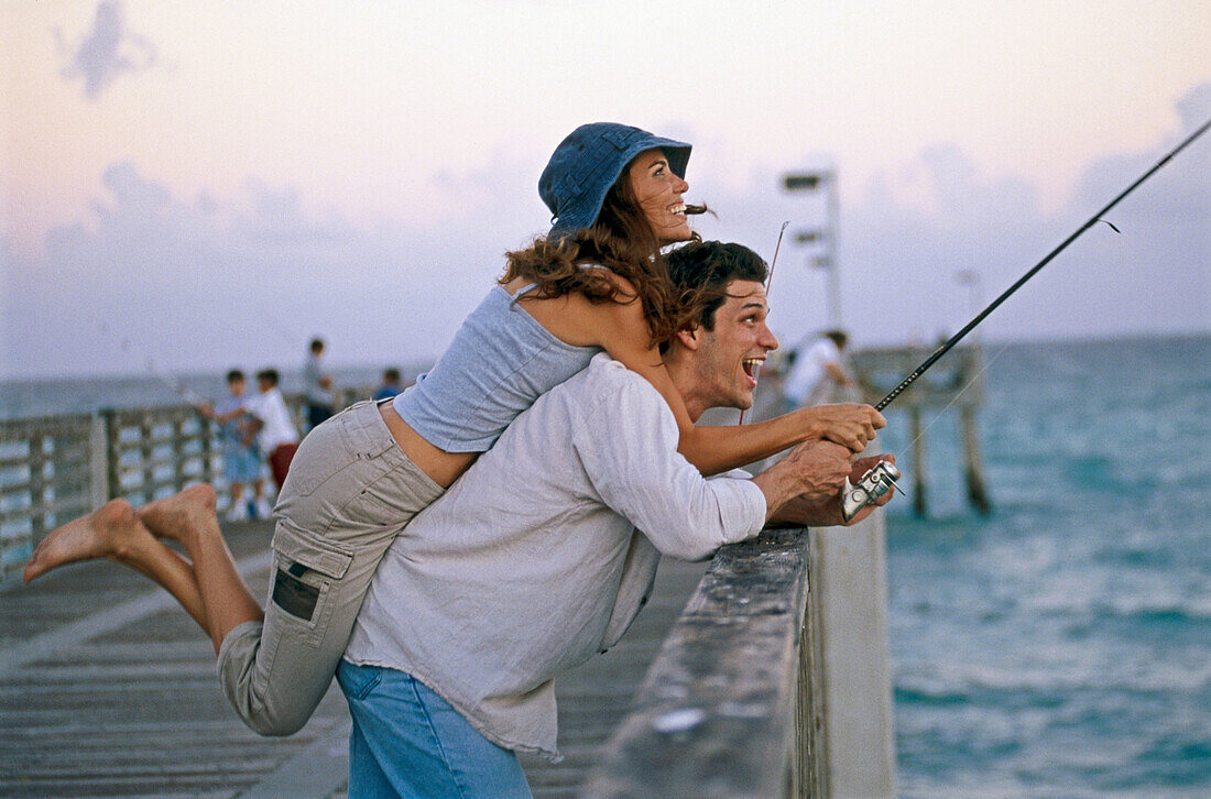 Couple fishing and laughing on a pier