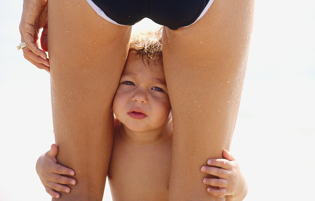 child looking between his mothers legs