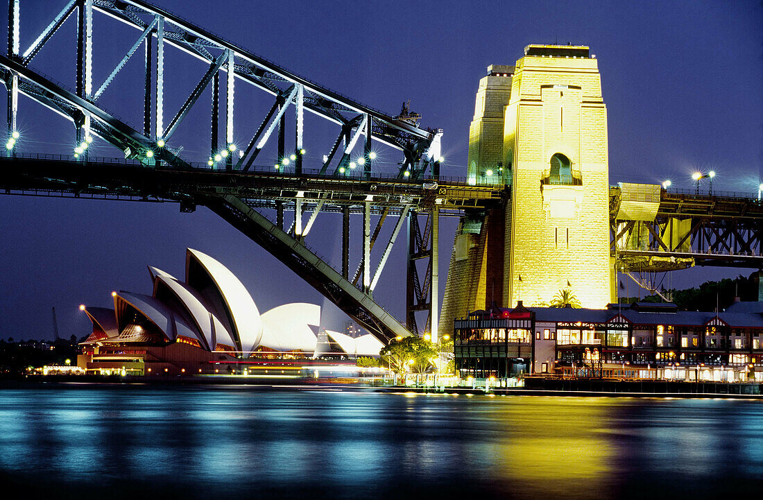 Sydney Harbour Bridge and Sydney Opera House shells against a deep electric blue sky at dusk. Sydney, Australia