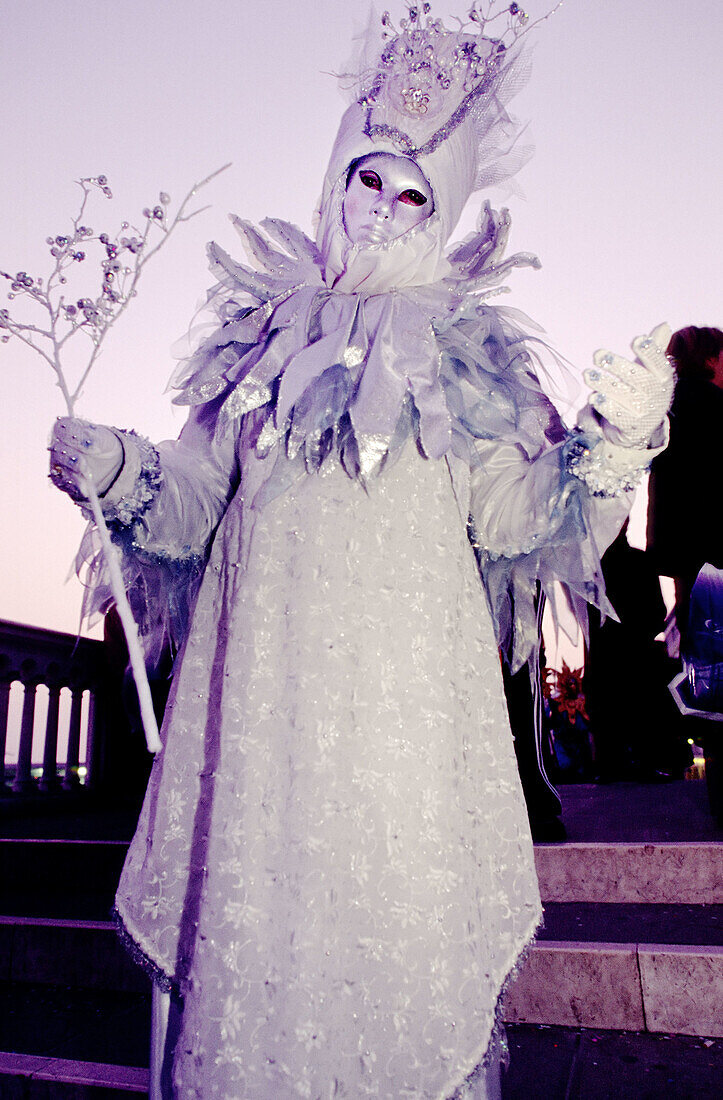 Person in a pearly white silver and blue coloured costume at a yearly carnival in Venice. Italy