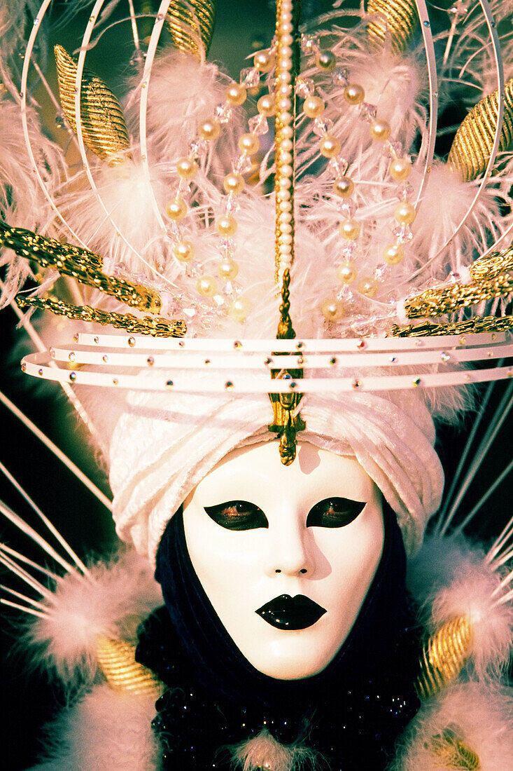 One person in an oriental themed white mask with elaborate feathers at yearly carnival in Venice, Italy