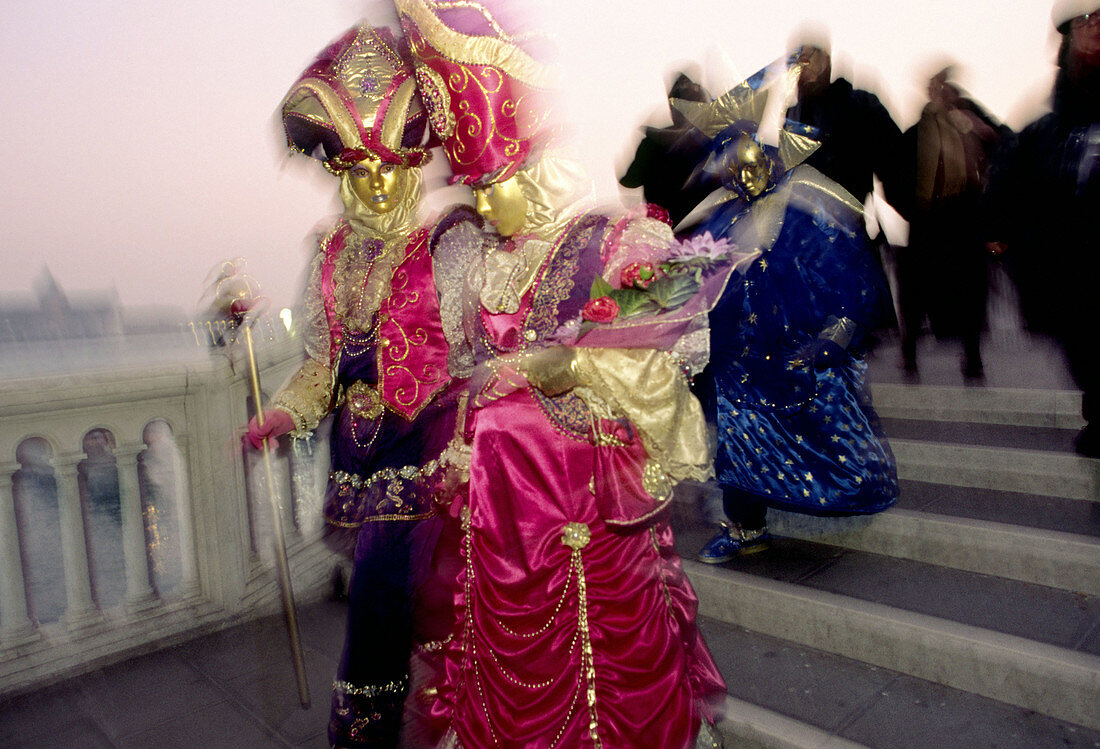 Two people in vivid colour costumes at masquerade in Venice, Italy