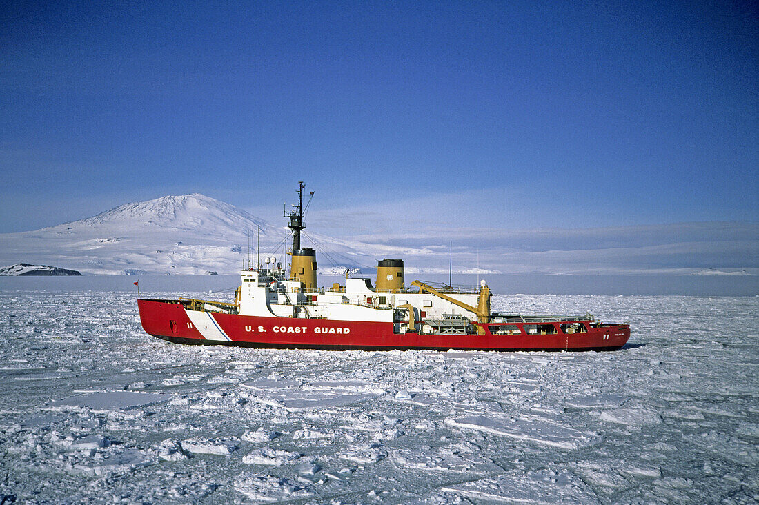 US Coast Guard cutter in ice: its responsible for braking the channel into McMurdo harbour so resupply and refueling can take place safely for McMurdo station; Mt. Erebus in background, Antarctica