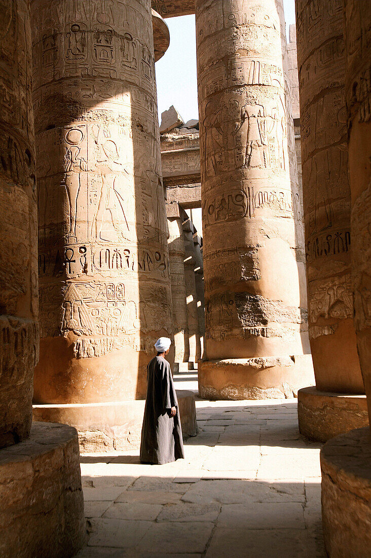 A caretaker at Karnak surveys the massive columns. Luxor. Egypt