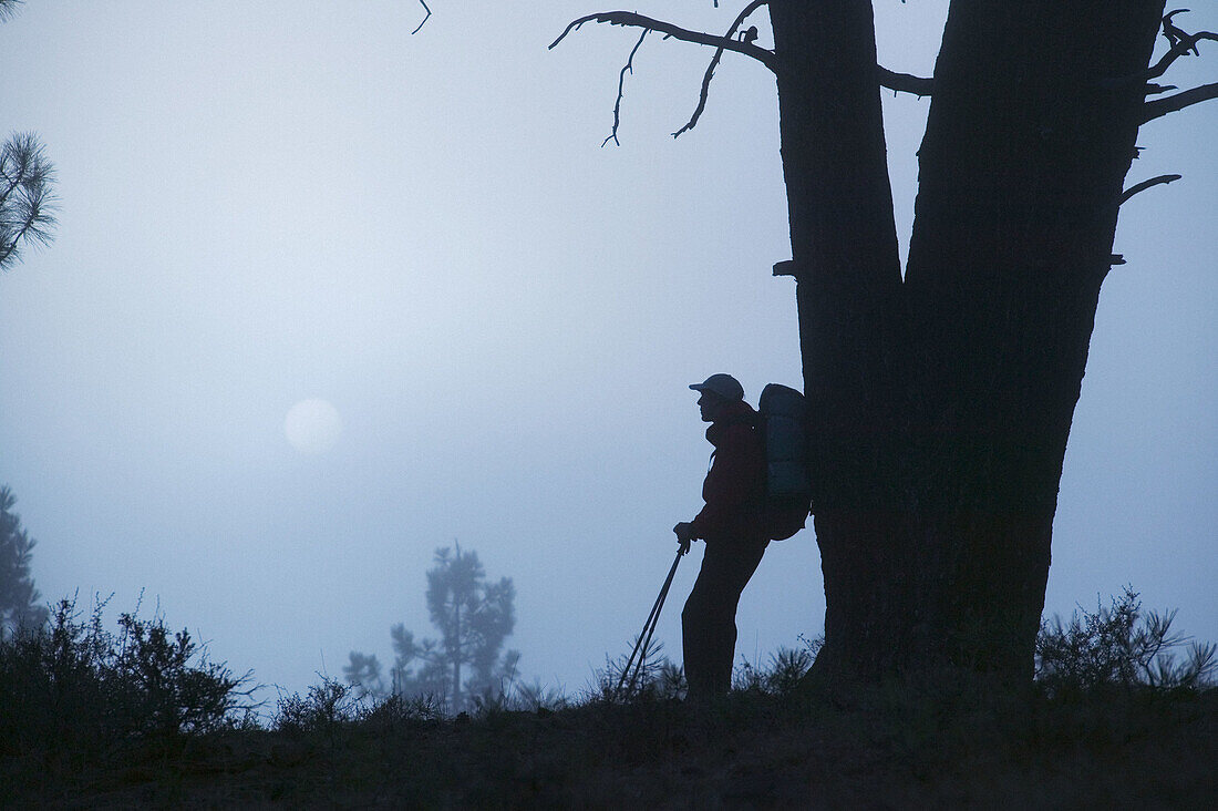 A man hiking at night with the full moon.