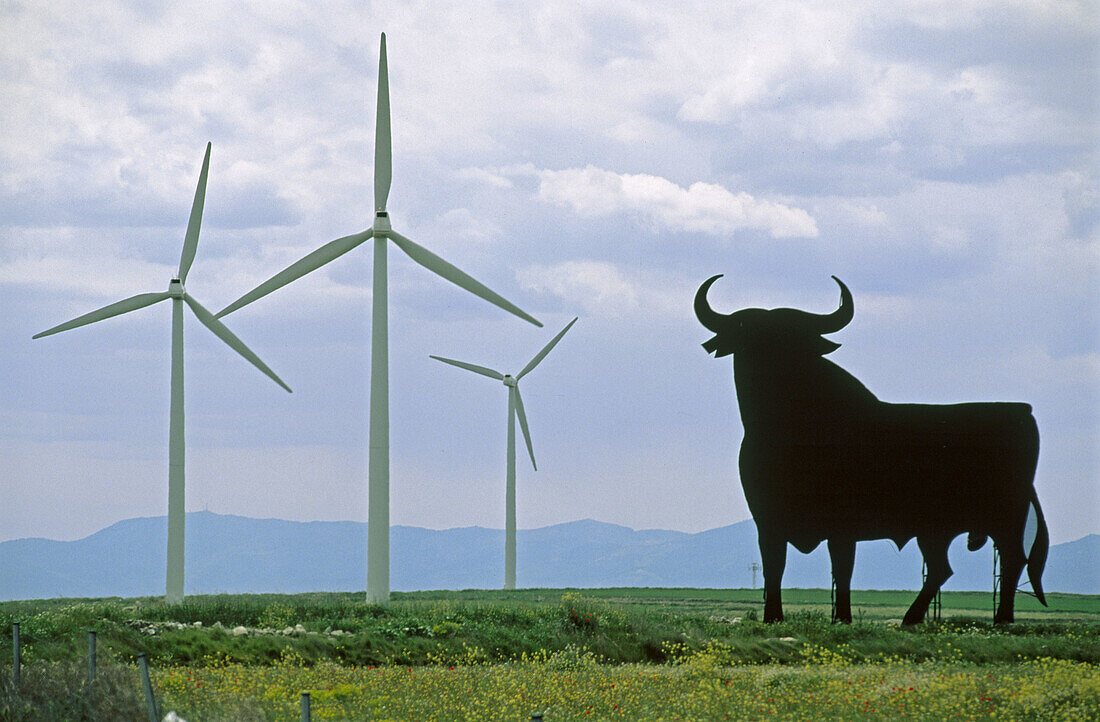 Bull silhouette, typical advertising of Spanish sherry Osborne, and wind turbines by windfarm. Zaragoza province, Aragón, Spain