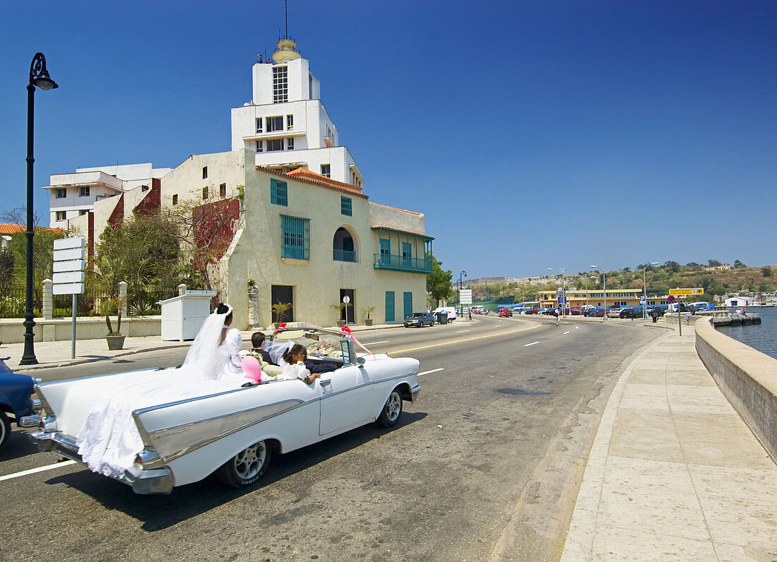 Wedding party on wheels, new bride atop white convertible in Havana. Cuba