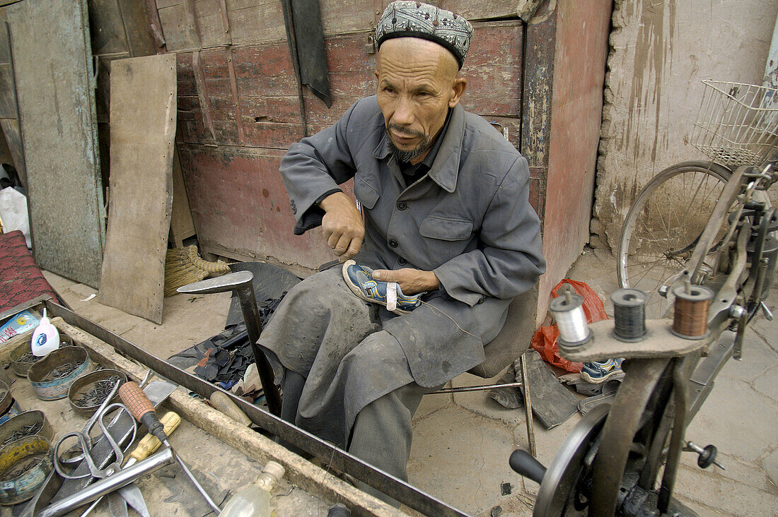 A uigur cobbler repair a shoe in Kashgar downtown. Kashgar city. Xinjiang province. China. Asia.