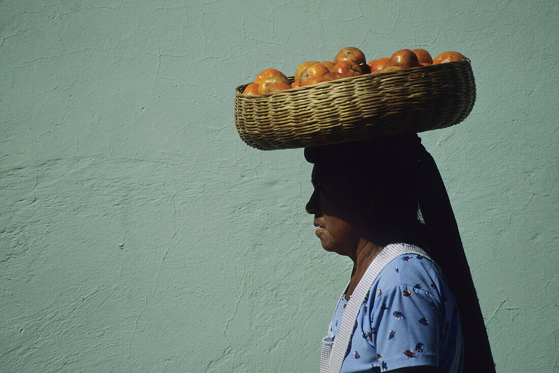 Guatemalian woman wearing fruit basket on head.