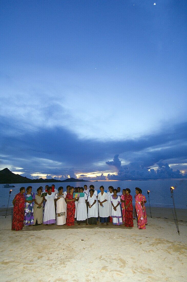 Naqumu Village Church Choir sings to an audience at sunset at the Nukubati Island Resort, Fiji Islands