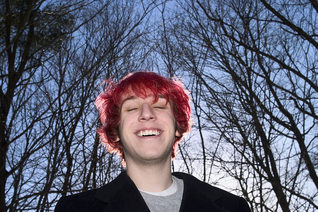 Teen boy, with dyed red hair, standing and posing outside