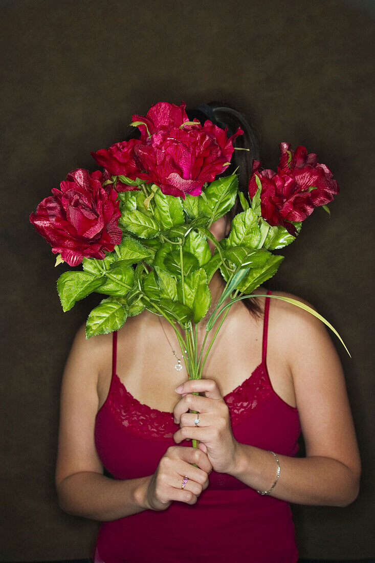 Young Asian woman holding a bouquet of flowers in front of her face