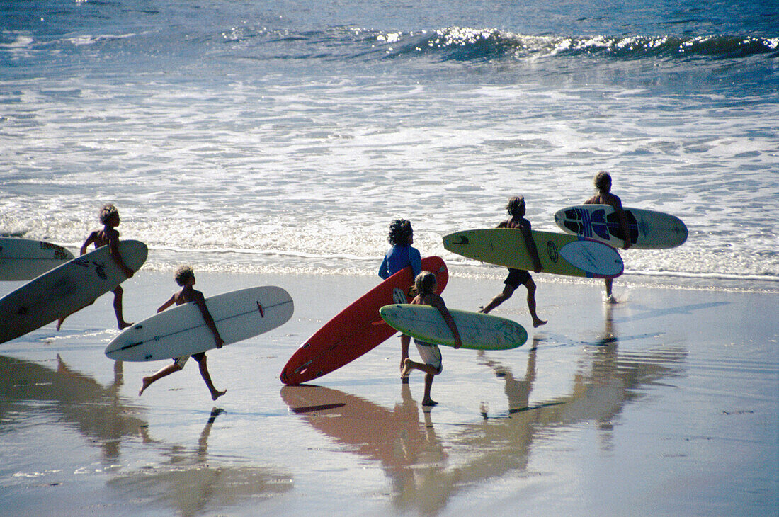 Surfers running into the water, Noosa, Queensland, Australia