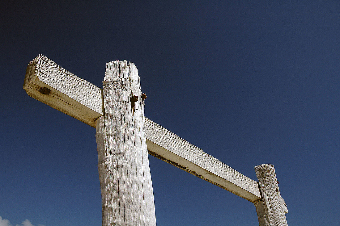 Weathered white wooden pylons against blue sky