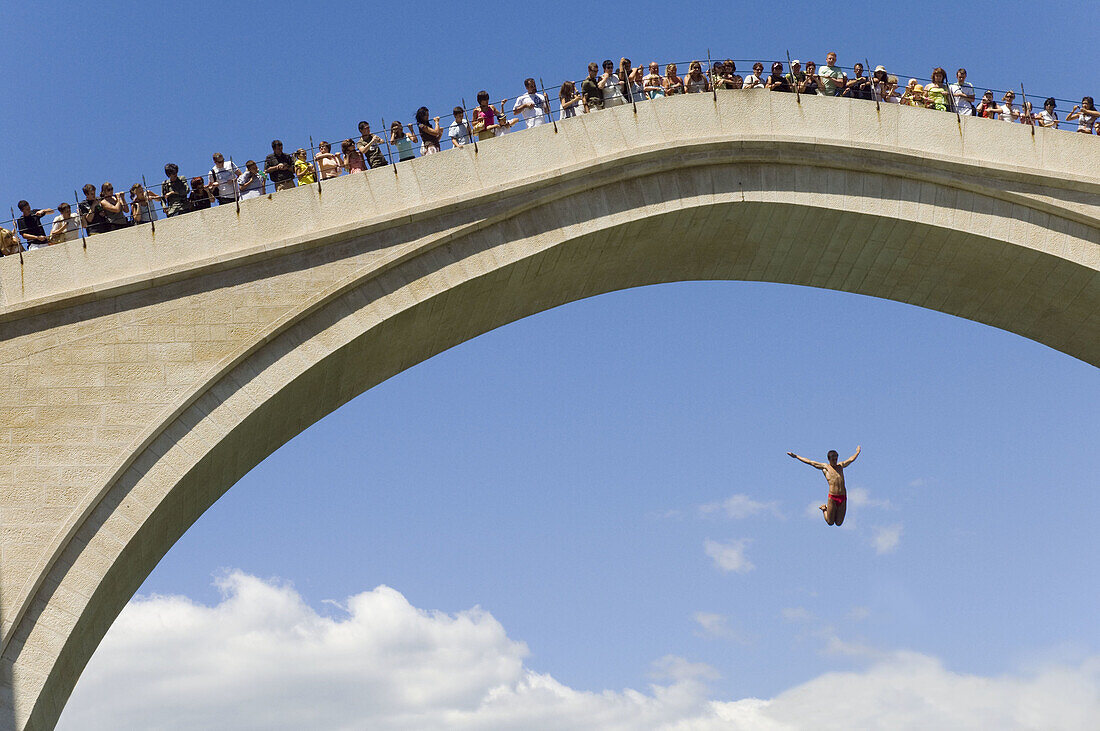 Tourists watch a man diving from the The new Old Bridge into the river Neretva Mostar Bosnia and Herzogovina