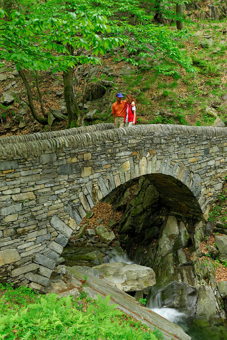 Paar geht über Steinbrücke, Tessin, Schweiz